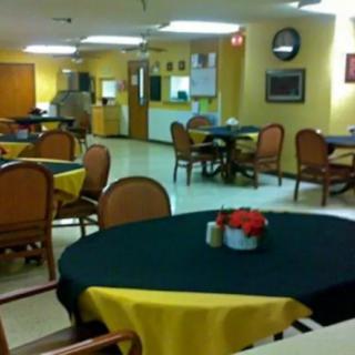 An empty dining room with tables and chairs, decorated with tablecloths and a centerpiece.