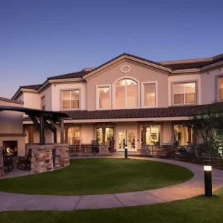A well-lit house with a landscaped garden during the evening.