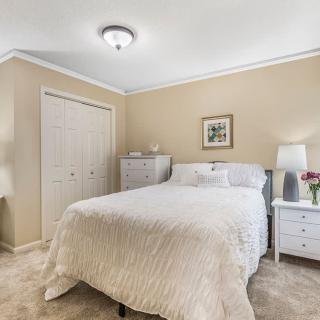 A cozy bedroom with neutral colors and simple decor, featuring a bed, nightstands, and lamps.