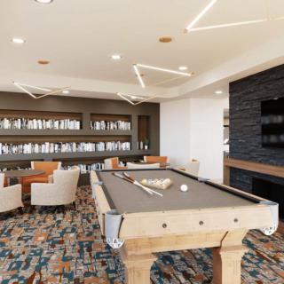 A modern lounge area featuring a billiards table and library with comfortable seating.