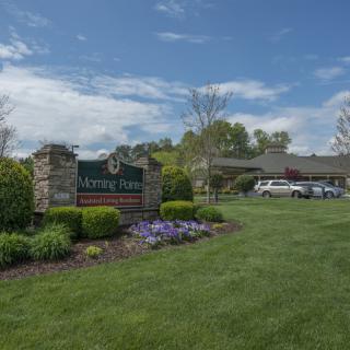 A well-maintained garden with a sign and building in the background under a partly cloudy sky.