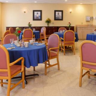 A cozy dining area with tables covered in blue tablecloths and surrounded by padded chairs.