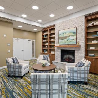 A cozy living room with a fireplace, surrounded by bookshelves and comfortable seating.