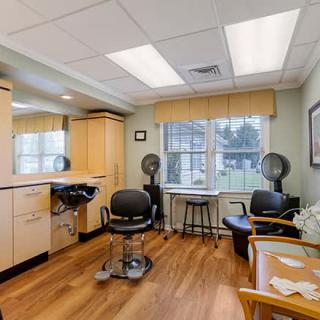 An interior view of a hair salon featuring styling chairs, mirrors, and hair dryers.