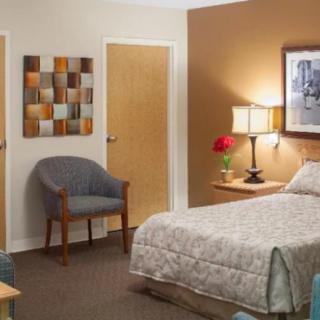 A cozy bedroom with a bed, lamp, chair, and decorative wall art.