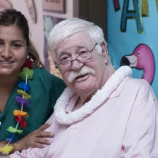 An older man and a woman smiling together at a tropical-themed event.