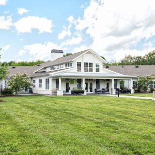 A beautiful countryside home with a well-maintained lawn and a clear, cloudy sky.