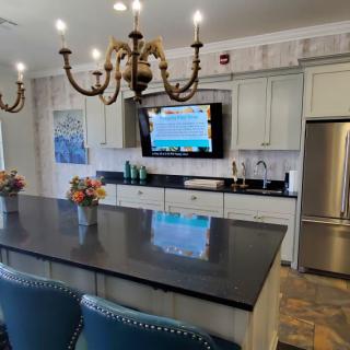 A modern kitchen with a large island, elegant chandelier, and sleek appliances.