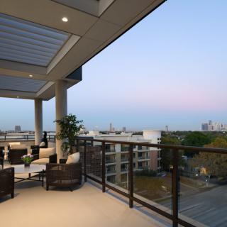 A spacious balcony with comfortable seating overlooking a cityscape at dusk.