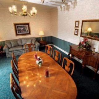 A spacious and elegantly arranged dining room featuring a large wooden table surrounded by chairs, complemented by soft lighting and decorative elements.