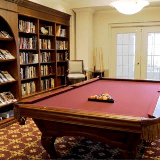 A cozy room featuring a pool table and bookshelves filled with books.