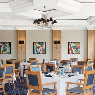 Elegant dining room with neatly set tables and colorful wall art.