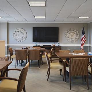 A modern conference room with tables, chairs, a large screen, and an American flag.