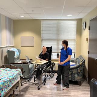 A patient in a wheelchair and a nurse in a healthcare room.
