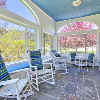 A serene sunroom featuring rocking chairs and a beautiful view of the outdoors.