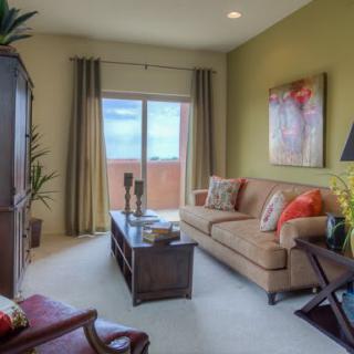 A cozy living room featuring a comfortable sofa, coffee table, and large window with curtains.