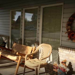 A cozy porch with chairs and decorations basking in the sunlight.