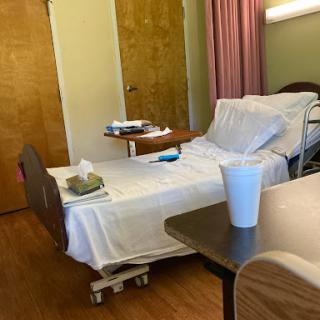 A view of a hospital patient room featuring a bed, bedside table, and medical equipment.