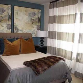 A cozy bedroom with stylish decor, featuring abstract artwork and warm tones.