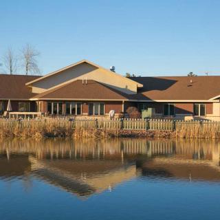 A house by a calm lake with its reflection visible in the water.