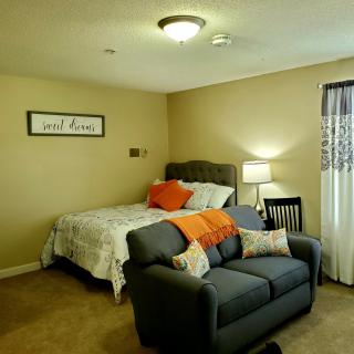 A cozy bedroom with a bed, sofa, and lamp creating a warm atmosphere.