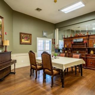 A vintage-style dining room with antique furniture and a piano.
