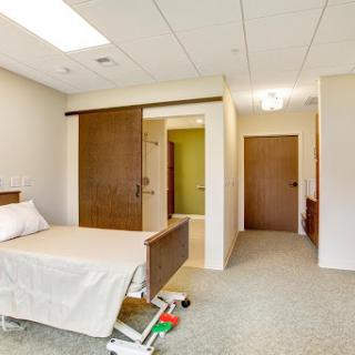 A modern hospital patient room featuring a bed, sliding door, and spacious layout.