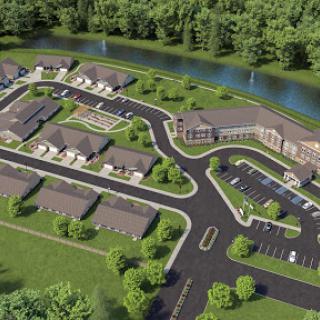 Aerial view of a planned residential community with landscaped grounds and winding roads near a river.