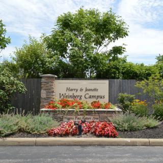 Entrance sign of the Hershey Campus surrounded by vibrant flowers and greenery.