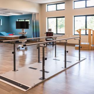 A well-equipped rehabilitation space featuring parallel bars and a wooden exercise aid, designed for physical therapy.