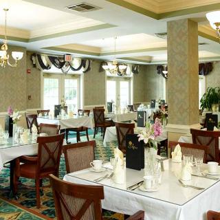 A formal dining room with elegantly set tables and chandeliers.