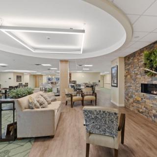 A modern lounge area featuring comfortable seating, a stone fireplace, and ample natural light.