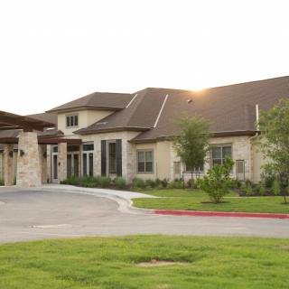A modern residential building with a spacious driveway and well-maintained landscape.
