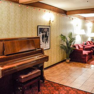 A cozy lounge with a vintage piano and comfortable seating arrangement.