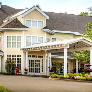 A large residential building with a covered entrance and landscaped garden.