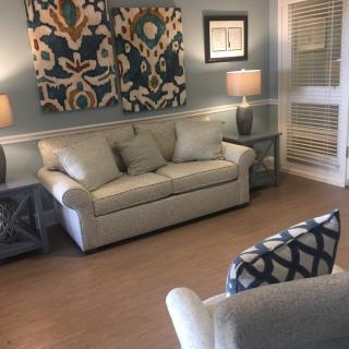 A cozy living room featuring a beige sofa, modern lamps, and decorative artwork on the walls.