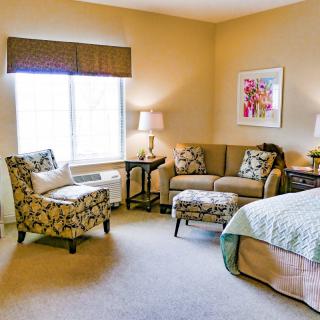 A cozy bedroom featuring a sofa, armchair, and bed with complementary decor.