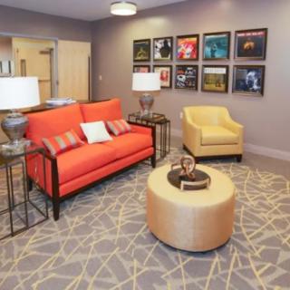A stylish living room featuring a vibrant orange sofa, a yellow armchair, and modern decor.
