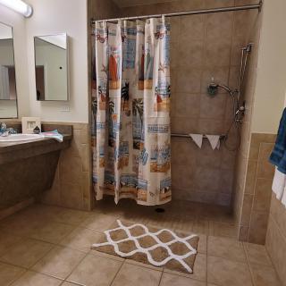 A bathroom with a colorful shower curtain and tiled walls.