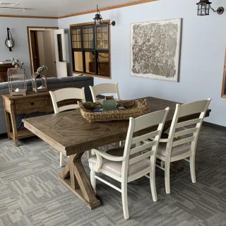 A rustic dining room with a wooden table and white chairs, featuring decorative elements.