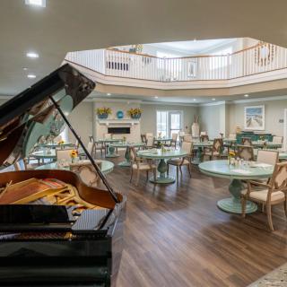 A spacious lobby with elegant seating and a grand piano, featuring modern decor and an upper-level balcony.