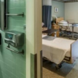 A hospital room with a neatly arranged bed and medical equipment.