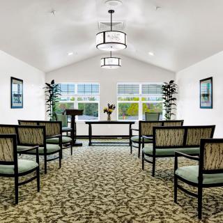 A serene chapel interior with a podium, elegant seating, and large windows.