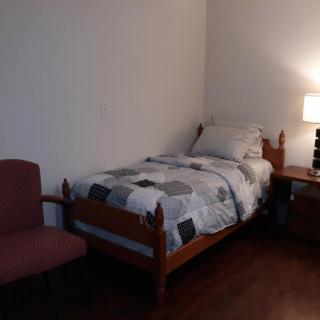 A minimalist bedroom with a single bed, nightstand, and lamp.