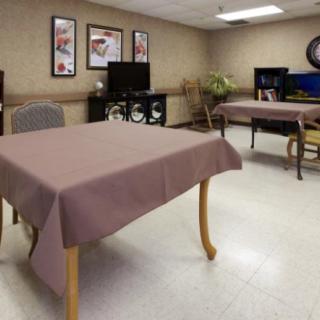 A dining area with tables covered in tablecloths and chairs, set indoors.
