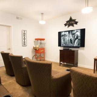 A cozy home theater setup with comfortable seating, a vintage movie playing on the TV, and a popcorn machine in the corner.