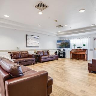 A spacious living room featuring leather sofas, hardwood floors, and a television.