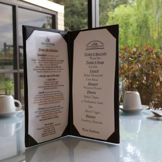 A restaurant menu displayed on a table with cups in the background.