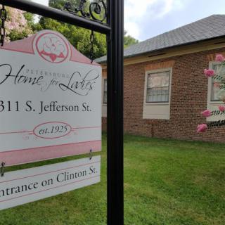 A real estate sign in front of a brick building with a well-maintained lawn.
