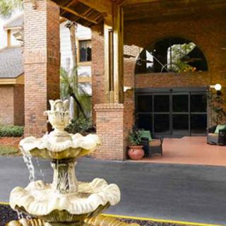 The entrance of a brick hotel with a decorative fountain in the foreground.